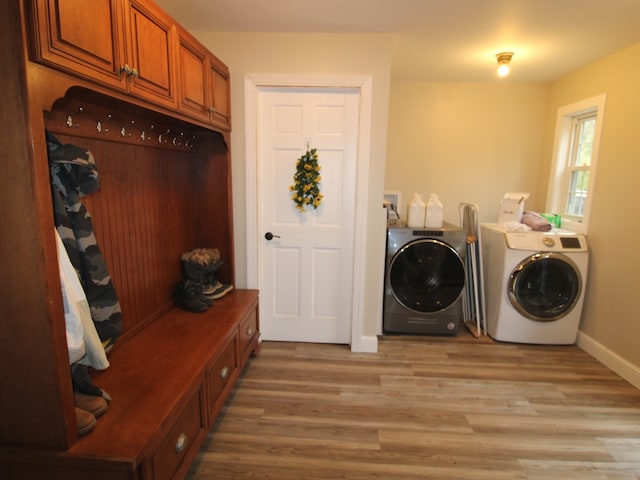 laundry area featuring separate washer and dryer, cabinets, and light hardwood / wood-style floors