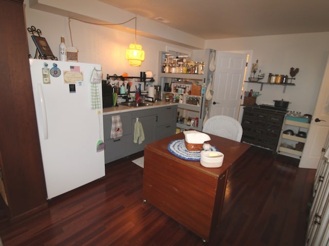 kitchen featuring dark wood-type flooring, sink, decorative light fixtures, and white fridge