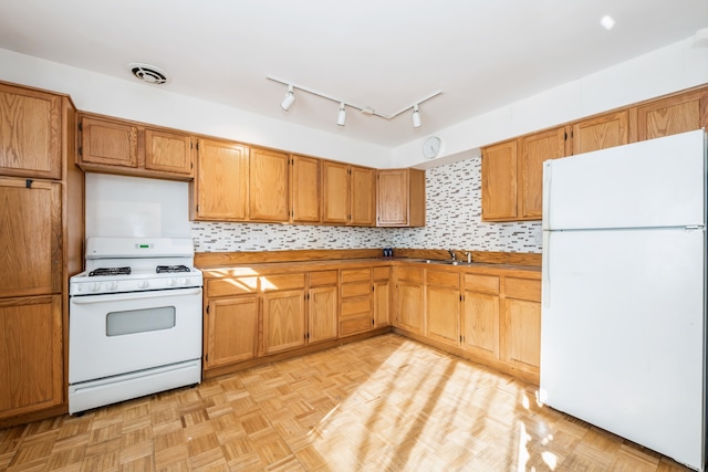 kitchen featuring backsplash, sink, light parquet flooring, and white appliances