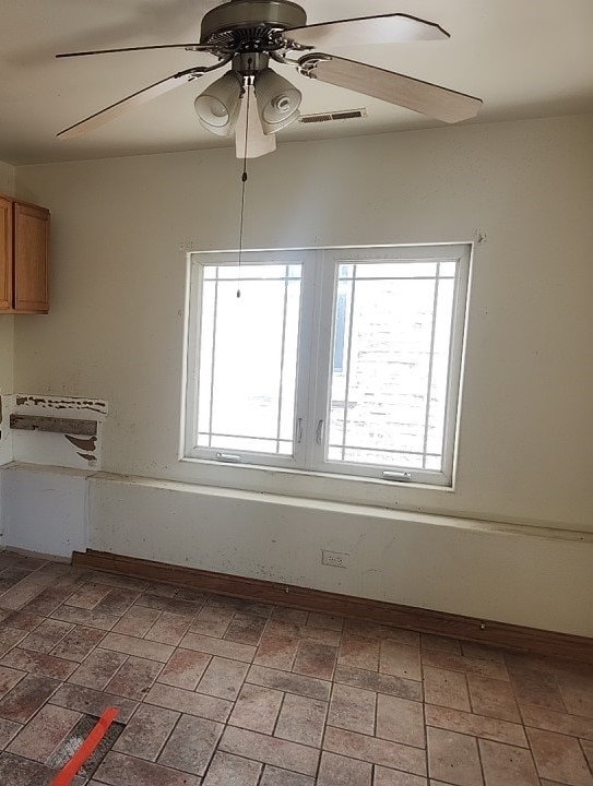 empty room with ceiling fan and plenty of natural light