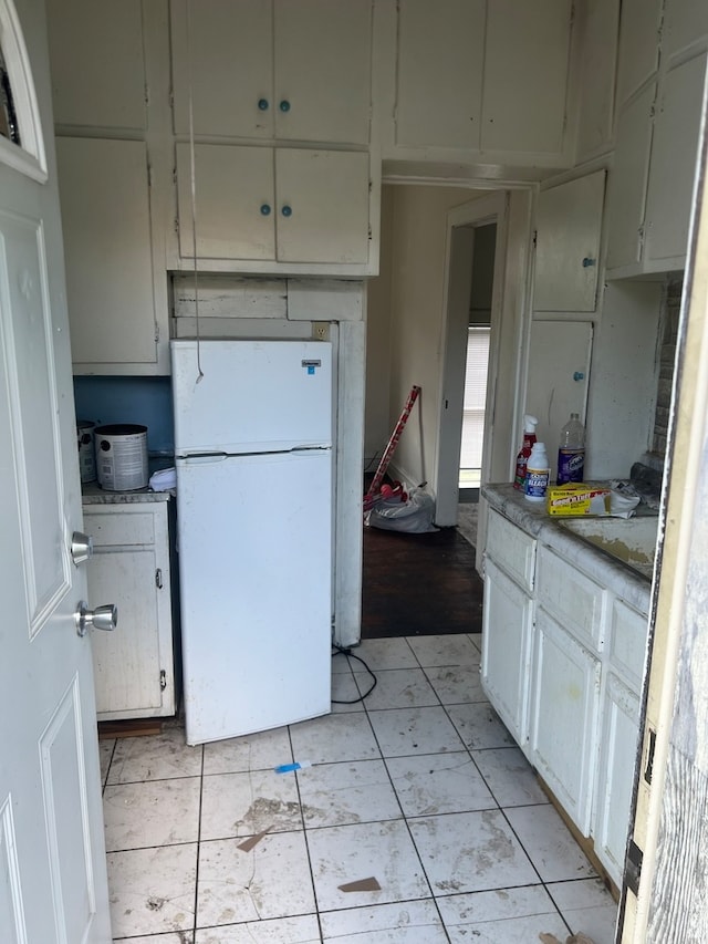 kitchen featuring white cabinets, white fridge, and light tile patterned floors