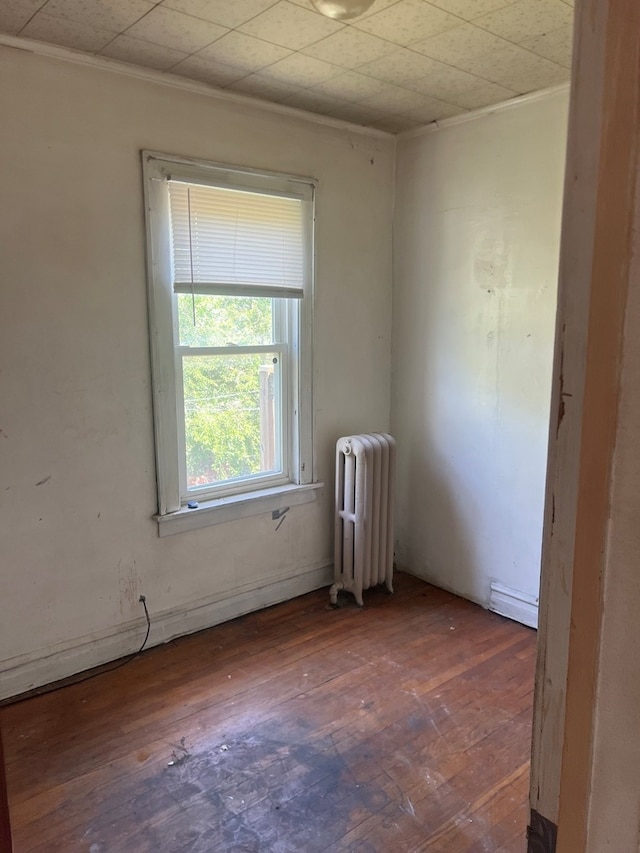 empty room featuring crown molding, radiator heating unit, and dark hardwood / wood-style flooring