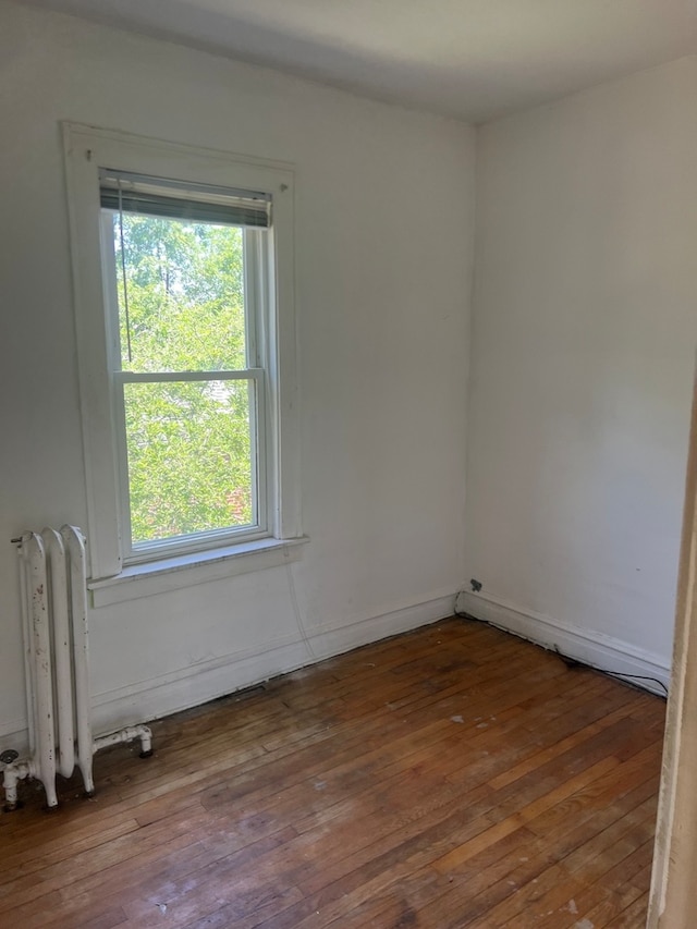 spare room with radiator heating unit and hardwood / wood-style flooring