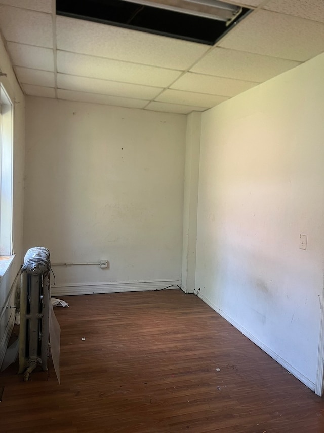 spare room featuring a drop ceiling and dark wood-type flooring