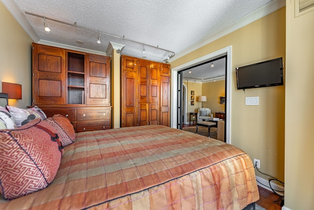 bedroom with a closet, a textured ceiling, hardwood / wood-style floors, and rail lighting