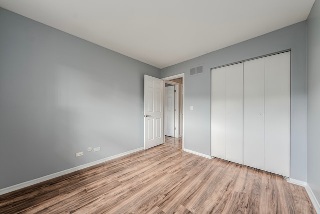 unfurnished bedroom with a closet and light wood-type flooring