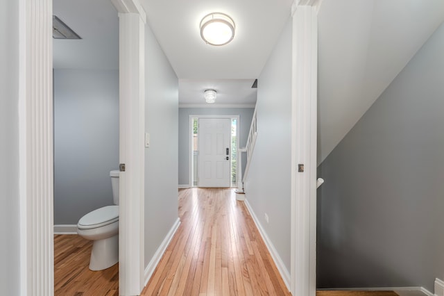 hallway with crown molding and light hardwood / wood-style flooring