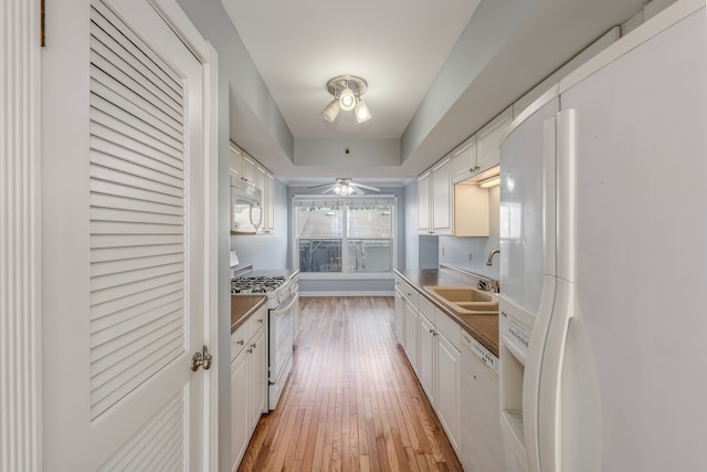 kitchen with white appliances, white cabinetry, and sink