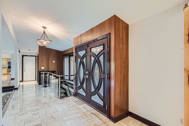 foyer entrance featuring a notable chandelier and wood walls