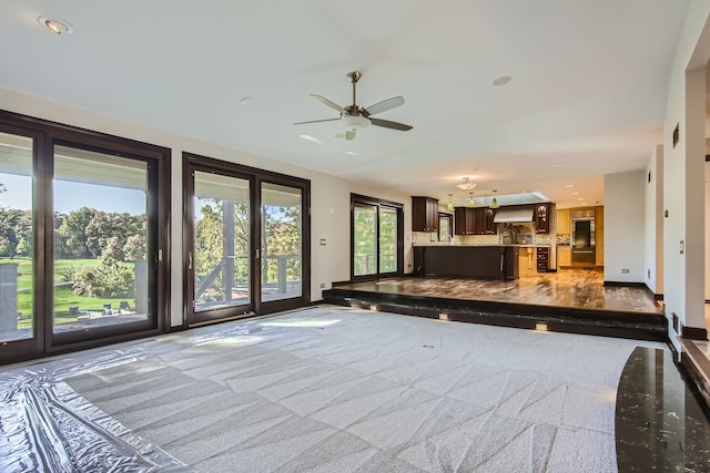 unfurnished living room featuring carpet floors and ceiling fan