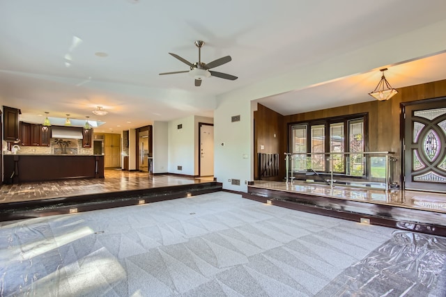 interior space with wooden walls, carpet floors, and ceiling fan