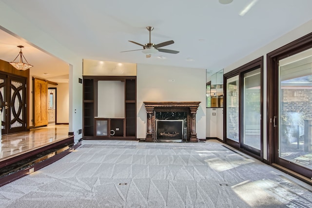 unfurnished living room featuring a premium fireplace, carpet floors, and ceiling fan