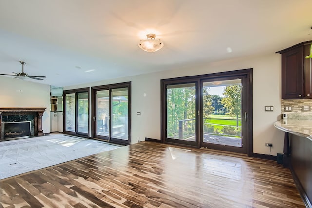 unfurnished living room with ceiling fan, wood-type flooring, a wealth of natural light, and a fireplace