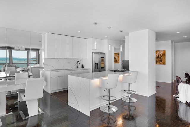 kitchen with white cabinets, tasteful backsplash, pendant lighting, high end fridge, and sink