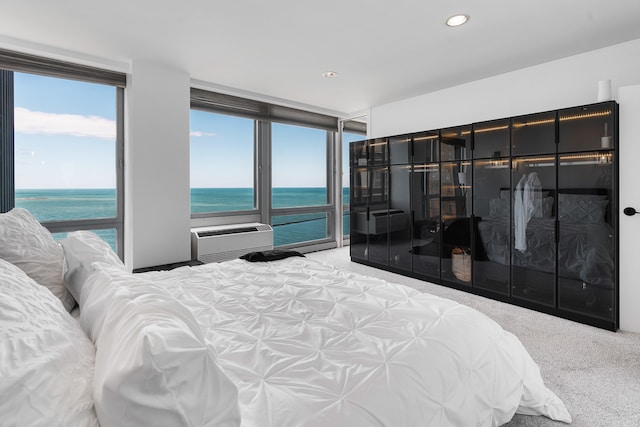 bedroom with a wall mounted air conditioner, a water view, and carpet flooring