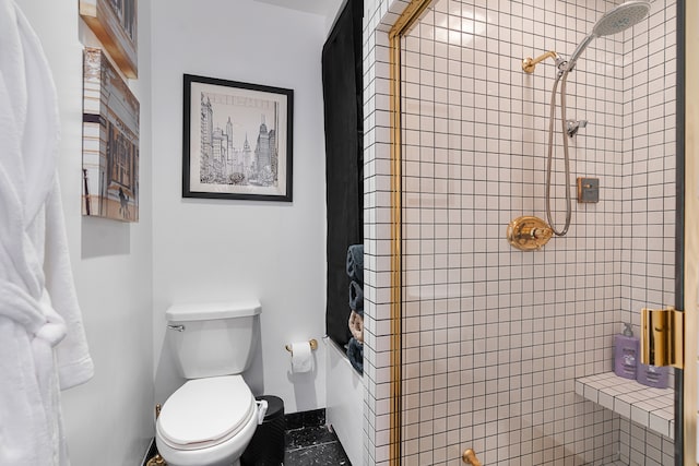 bathroom featuring a tile shower and toilet