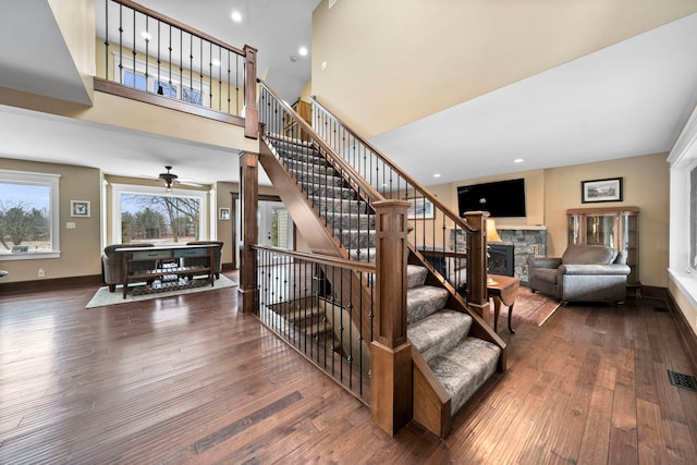 stairs with wood-type flooring, a towering ceiling, and a fireplace