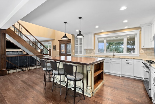 kitchen featuring high end range, sink, white cabinets, and tasteful backsplash