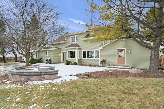 snow covered rear of property featuring a yard