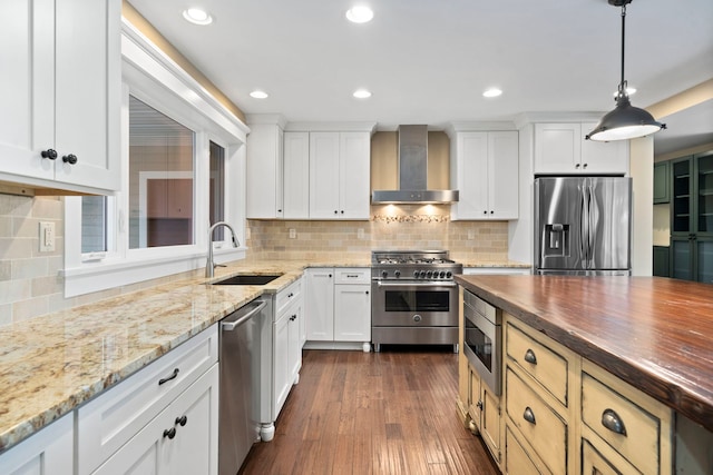 kitchen featuring appliances with stainless steel finishes, decorative backsplash, sink, wall chimney exhaust hood, and wood counters