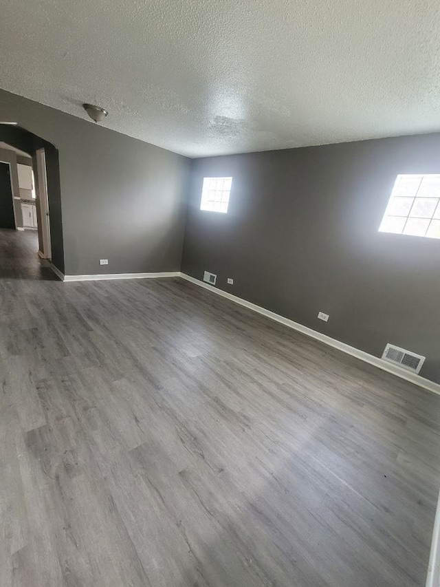 unfurnished room with a textured ceiling and hardwood / wood-style floors