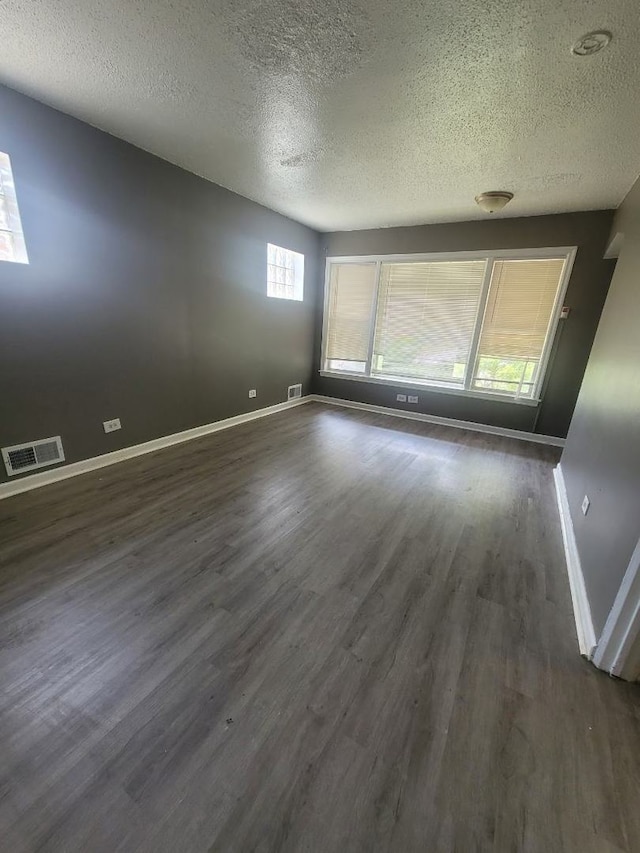 unfurnished room featuring a textured ceiling and dark hardwood / wood-style floors