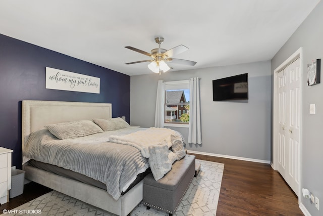 bedroom with dark wood-type flooring, ceiling fan, and a closet