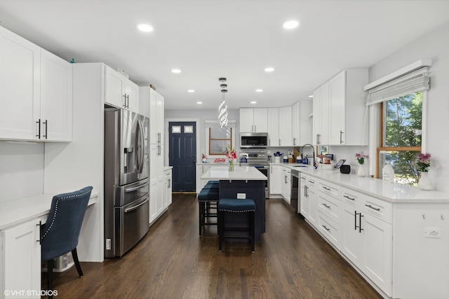 kitchen featuring hanging light fixtures, stainless steel appliances, a breakfast bar, a center island, and dark hardwood / wood-style flooring