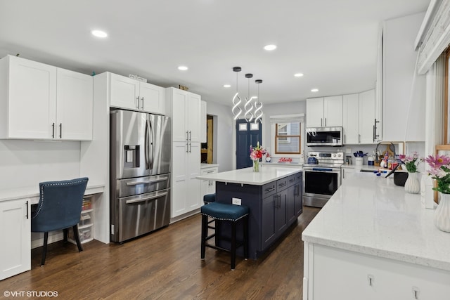 kitchen with a kitchen island, dark wood-type flooring, stainless steel appliances, decorative light fixtures, and white cabinetry