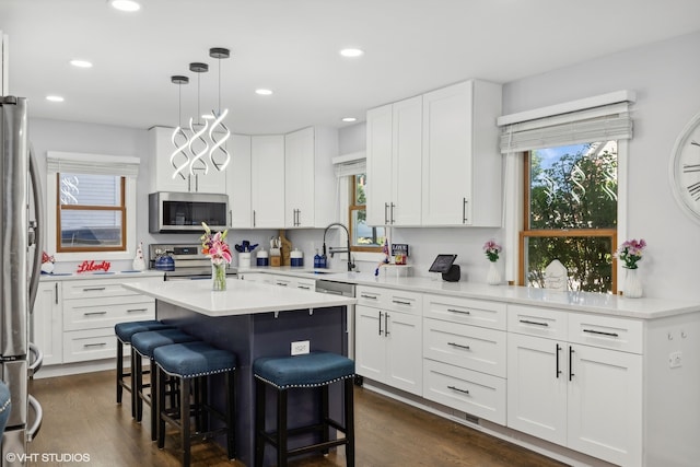 kitchen featuring white cabinetry, stainless steel appliances, decorative light fixtures, and dark hardwood / wood-style flooring