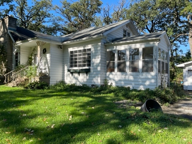 view of property exterior featuring a yard and a sunroom