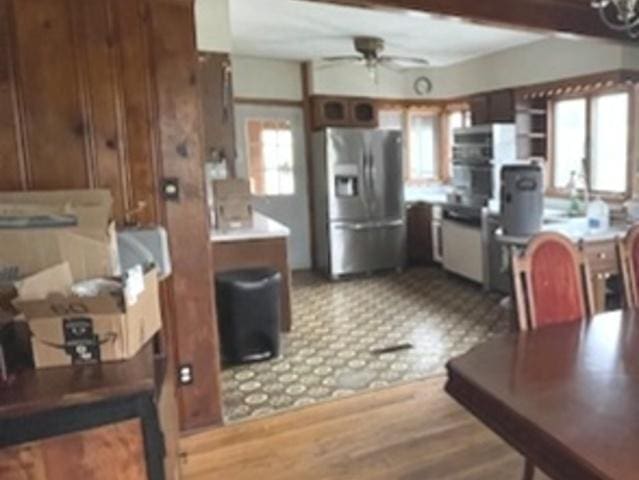 kitchen featuring stainless steel fridge, a ceiling fan, and wooden walls
