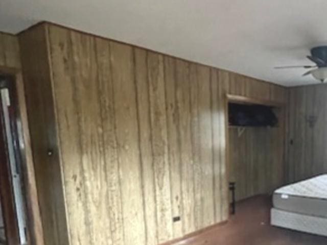 bedroom featuring wooden walls, a closet, and ceiling fan
