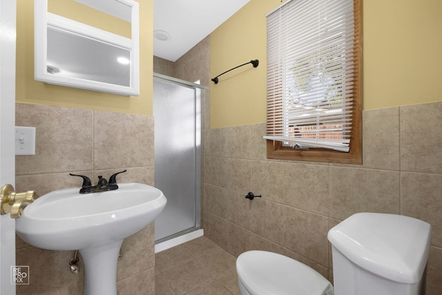 bathroom featuring toilet, tile walls, and a shower with door