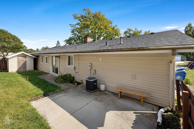 rear view of property featuring a storage unit, a lawn, cooling unit, and a patio