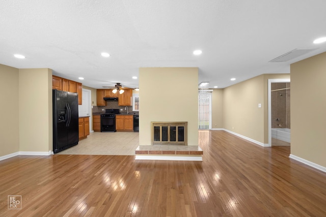 unfurnished living room with light wood-type flooring, sink, and ceiling fan