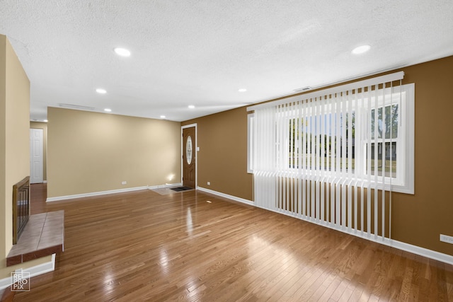 unfurnished living room featuring wood-type flooring and a textured ceiling