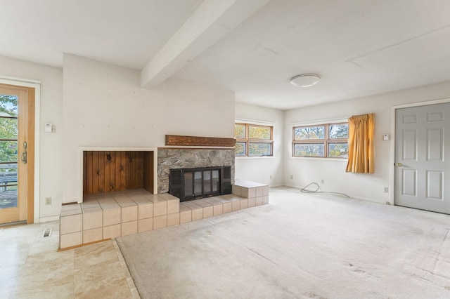 living room featuring beamed ceiling, plenty of natural light, a stone fireplace, and light tile patterned floors