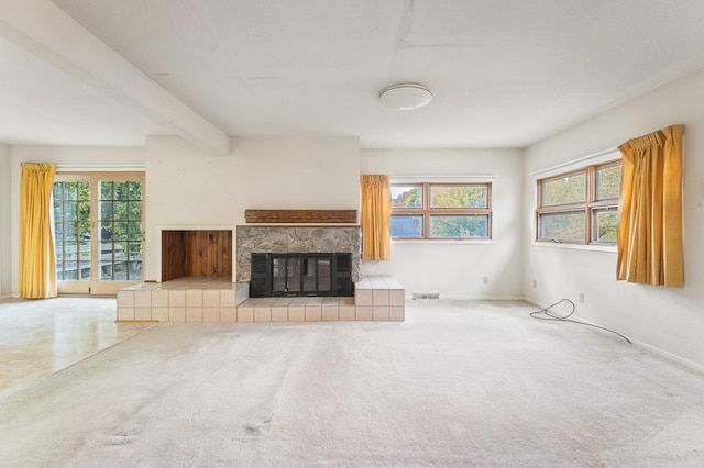 unfurnished living room with carpet flooring, a tile fireplace, and beamed ceiling