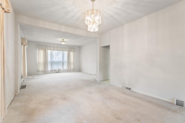 carpeted empty room with a chandelier