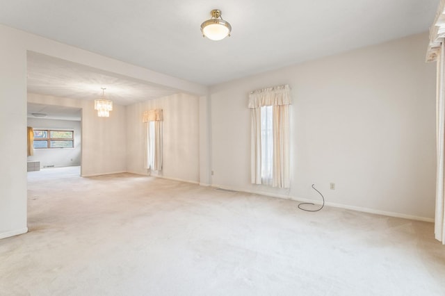 carpeted empty room with a notable chandelier