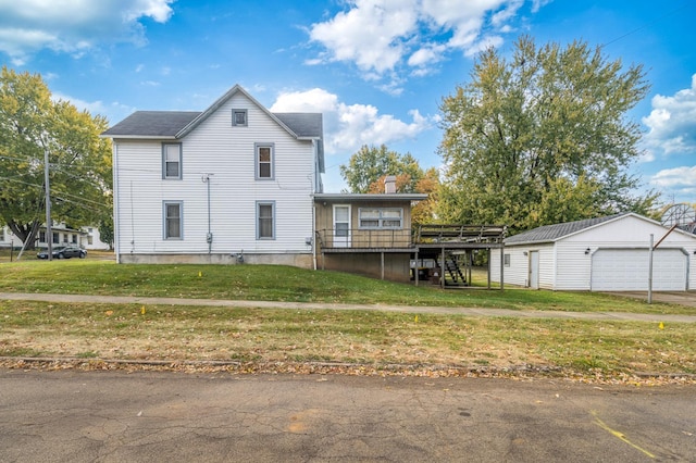 rear view of property with a lawn, a garage, an outbuilding, and a wooden deck