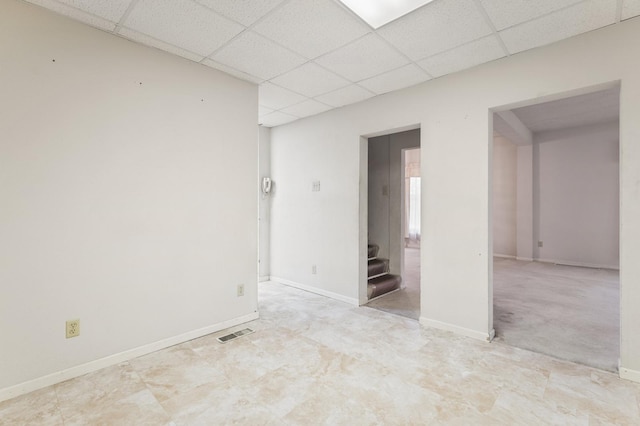 carpeted spare room featuring a paneled ceiling