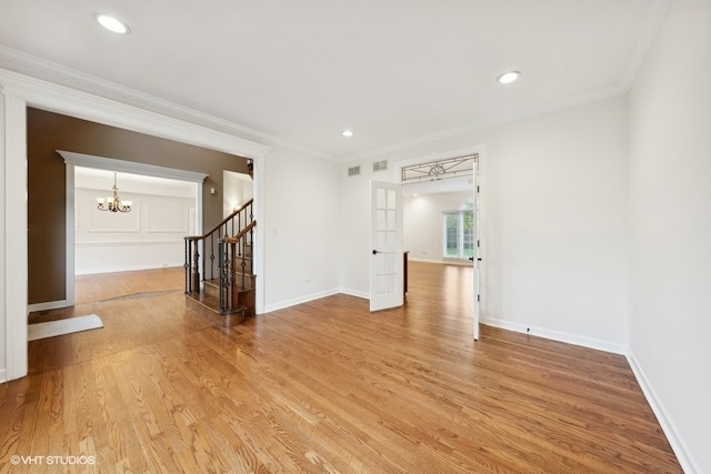 unfurnished room featuring ornamental molding, an inviting chandelier, hardwood / wood-style floors, and french doors