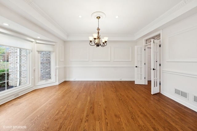 unfurnished dining area with crown molding, a notable chandelier, and wood-type flooring