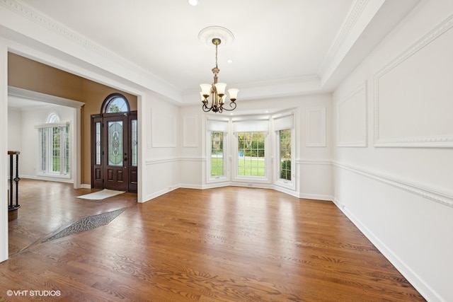 interior space with an inviting chandelier, ornamental molding, and hardwood / wood-style flooring