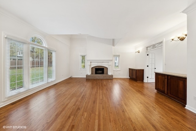 unfurnished living room featuring light hardwood / wood-style flooring, ornamental molding, and a wealth of natural light