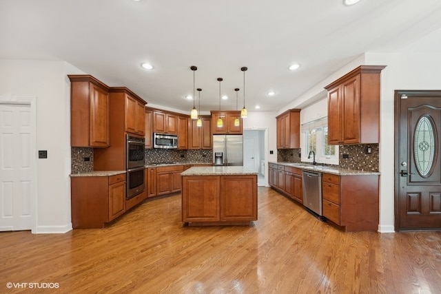 kitchen featuring sink, a center island, decorative light fixtures, appliances with stainless steel finishes, and light hardwood / wood-style floors