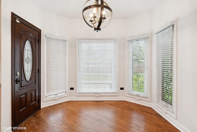 entrance foyer featuring a healthy amount of sunlight, dark hardwood / wood-style flooring, and a chandelier