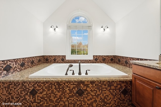 bathroom with vanity, lofted ceiling, and a relaxing tiled tub